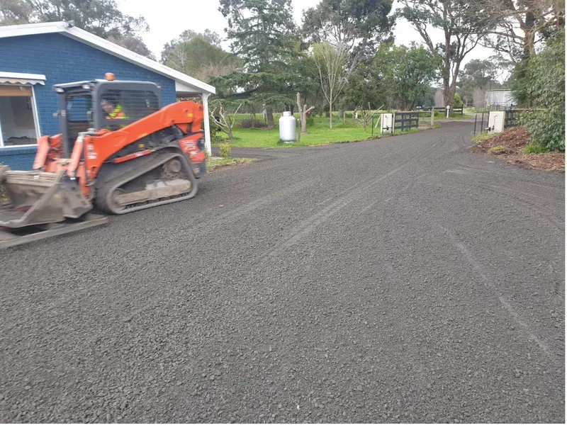 Skid-steer laying and grading metal on a residential driveway